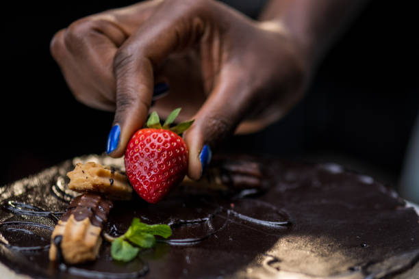 istock Woman's hand placing strawberry on mousse cake 1313659523