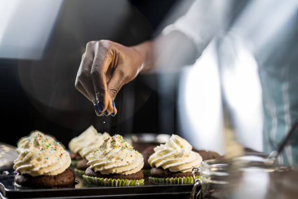 Woman's hand sprinkling hundreds and thousands on cupcake