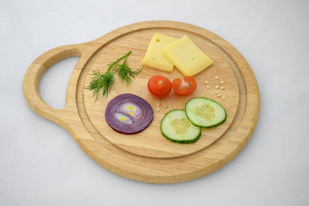 istock Cheese and vegetables on chopping board. Onion, cucumber and cherry tomato ingredients. 1313662705