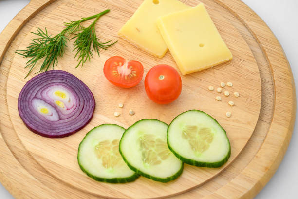 istock Cheese and vegetables on chopping board. Onion, cucumber and cherry tomato ingredients. 1313662707