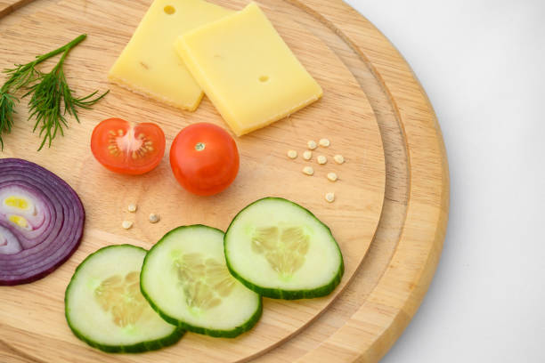 istock Cheese and vegetables on chopping board. Onion, cucumber and cherry tomato ingredients. 1313662726