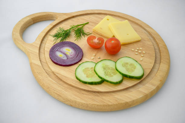 istock Cheese and vegetables on chopping board. Onion, cucumber and cherry tomato ingredients. 1313662736