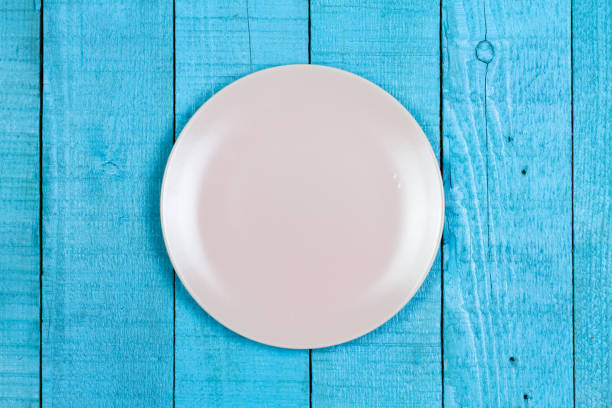 istock Empty pink ceramic plate on blue wooden background. 1313665266