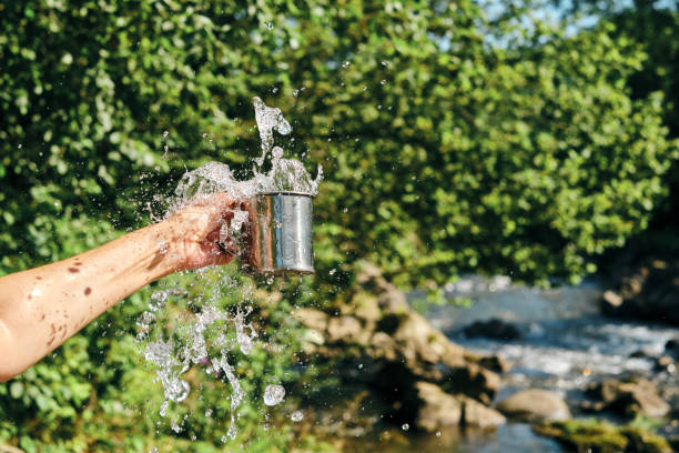 A splash of fresh water from a mug in the hands of a girl on the background of nature. Drinking water concept. A splash of freshness. Natural water. Healthy lifestyle. Cold water from a mountain river A splash of fresh water from a mug in the hands of a girl on the background of nature. Drinking water concept. A splash of freshness. Natural water. Healthy lifestyle. Cold water from a mountain river splash mountain stock pictures, royalty-free photos & images