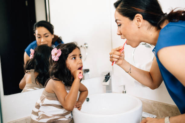 istock Mother and daughter brushing teeth 1313668064