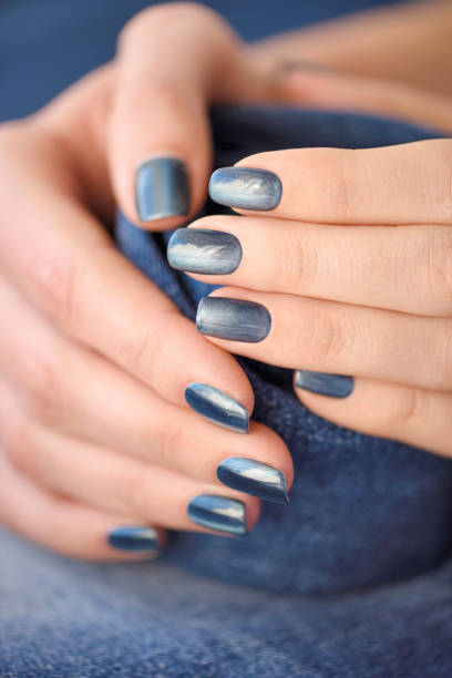 istock Hands with dark blue manicured nails on jeans textile background 1313668120