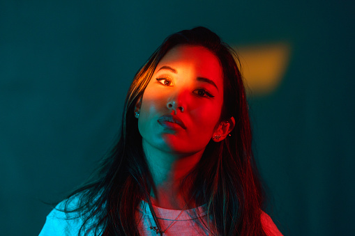 A portrait of a beautiful woman lit by neon colored lights.
