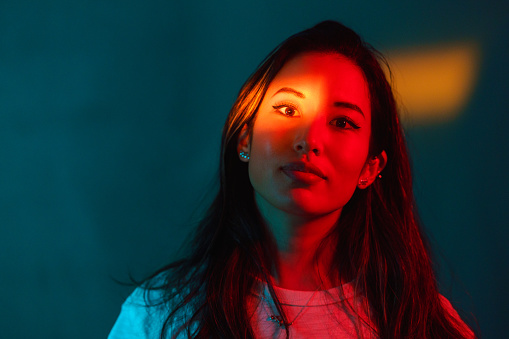 A portrait of a beautiful woman lit by neon colored lights.