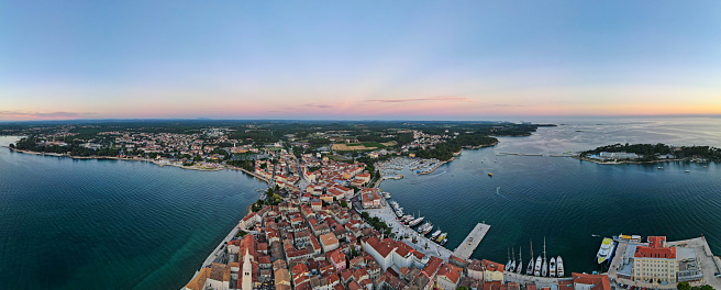 Mediterranean Croatian coastal port ancient city at sunset in summer, photographed in panoramic mode from above, Adriatic sea, Porec, seaside resort, popular destination.