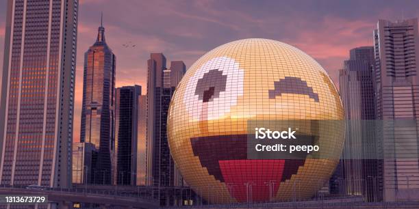 Building In Shape Of Smiling Emoji Blinking With Tongue Out In The Middle Of Downtown City Skyscrapers Stock Photo - Download Image Now