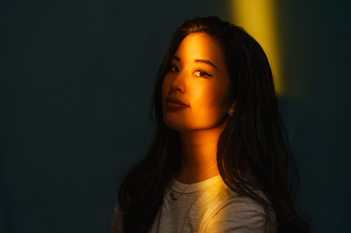 A high contrast portrait of a beautiful woman with warm light lighting her face.