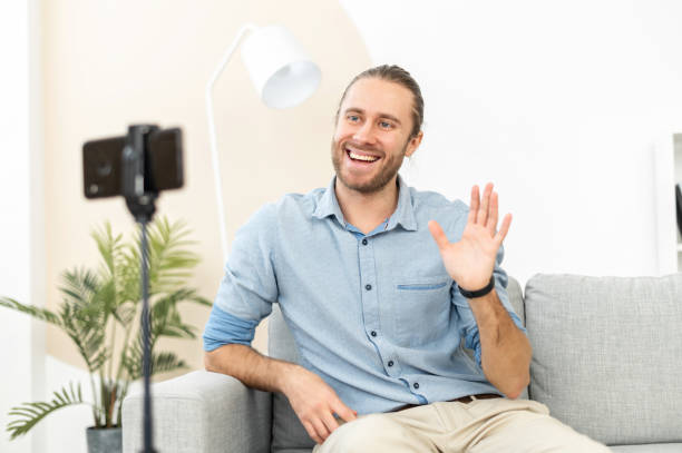 istock Open-minded man sitting on the sofa before the phone and waving the hand 1313677448