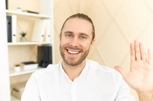 istock Young bearded hipster man is waving at the camera 1313677670