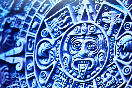 A round engraved stone with Aztec calendar on a wooden background