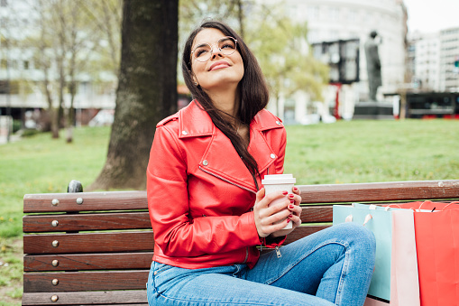Portrait of a smiling young woman taking a break after shopping in the city and enjoying coffee.