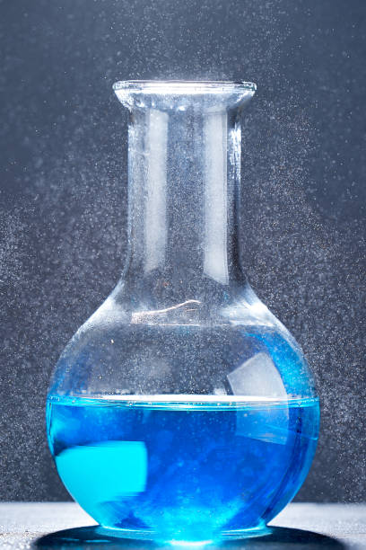 istock Glass flask with a blue liquid on gray background. 1313682936