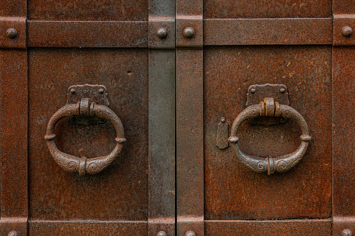 Close up of two rusty door handles on a rusty iron door