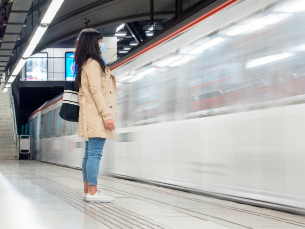 istock Woman standing on a subway platform with a metro train movingduring COVID 1313688103