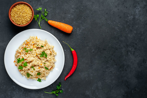 Bulgur with vegetables on a stone background with copy space for your text. Healthy eating