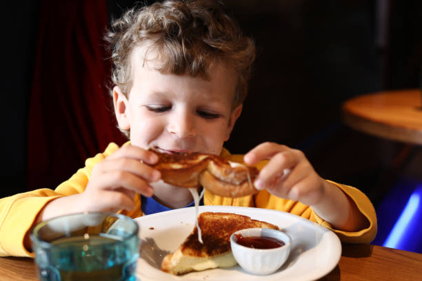 istock Boy eating a grilled cheese sandwich in a restaurant 1313690969