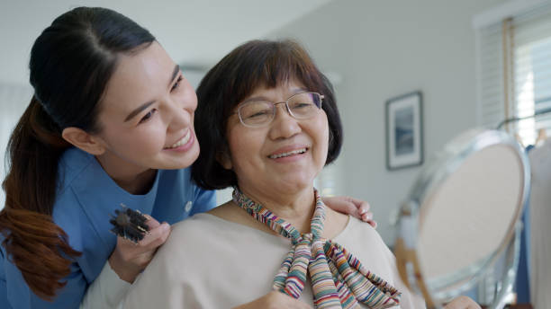 attraktive junge asiatische seniorin glücklich gesicht mit krankenschwester zu hause am morgen in routine-lifestyle, haarbürste nieren, asien pflege in-home-pflege freiwilligen, betreutes wohnen service-konzept. - senior citizen woman stock-fotos und bilder