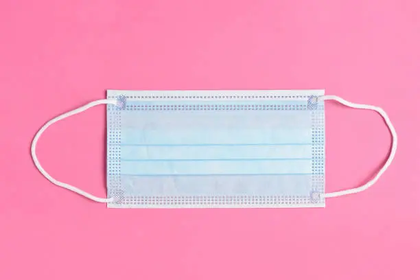 Blue Surgical Mask on a Pink Background, High angle view.