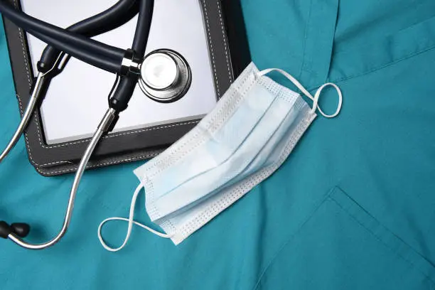 Stethoscope, surgical mask and medical tablet computer on a set of surgical greens, Scrubs.