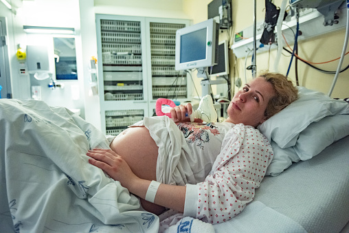 Pregnant woman in the hospital, using gas mask to reduce labour pain, preparation to childbirth, healthy pregnancy concept.