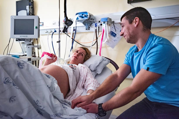 mulher em trabalho de parto na sala de parto, segurando a mão do marido. - delivery room - fotografias e filmes do acervo