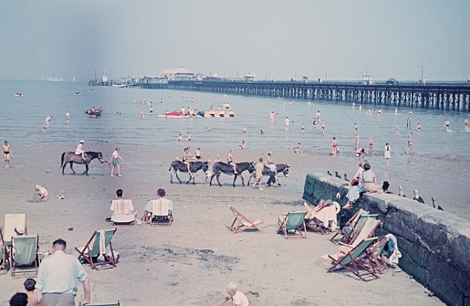 Brighton, East Sussex, England, UK, 1955. Beach scene with bathers, families, weekenders and holidaymakers in the famous southern English seaside resort of Brighton. In the background the Brighton Palace Pier.