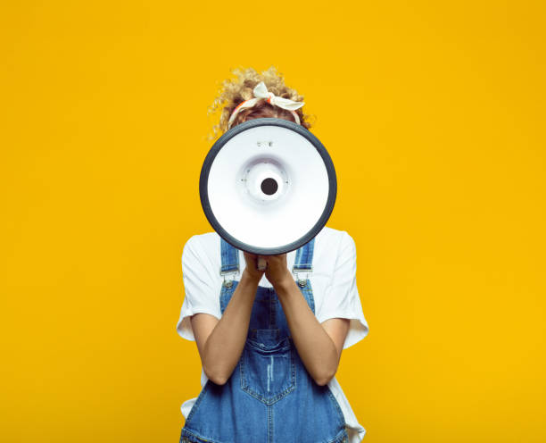 istock Young woman in dungarees shouting into megaphone 1313706043