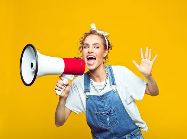 istock Young woman in dungarees shouting into megaphone 1313706130