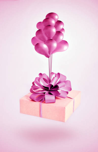 istock Cardboard gift box with pink bow and air ballons on pink background. 1313706583