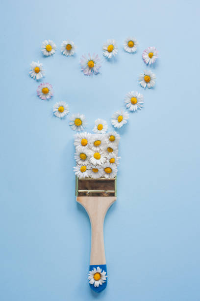 istock Creative layout of white flowers and paint brush on light blue background 1313707635