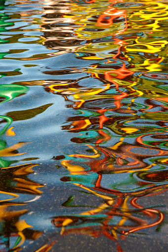 Multi colored water reflection under artificial lighting formed beautiful abstract graphic movement and wave pattern.
