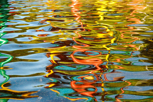 Multi colored water reflection under artificial lighting formed beautiful abstract graphic movement and wave pattern