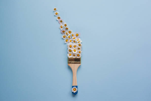 istock Creative layout of white flowers and paint brush on light blue background 1313708096