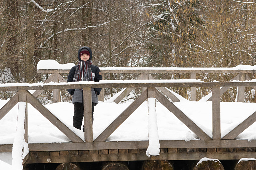 Boy 5 years old posing on a wooden bridge in the snow on the slope of the mountains. Selective focus. Tustan. Carpathians. Ukraine