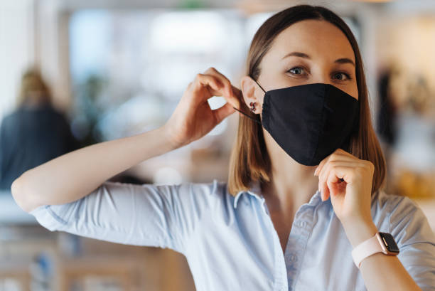 istock Woman put on mask indoors while looking to camera 1313715533