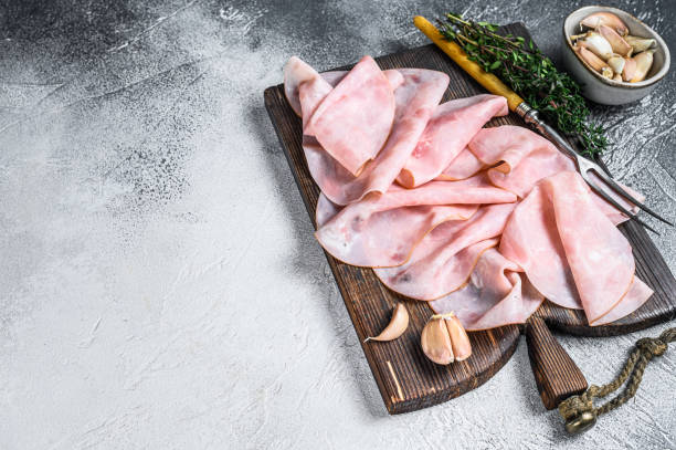 istock Ham Thin sliced on wooden cutting board with herbs. White background. Top view. Copy space 1313717754