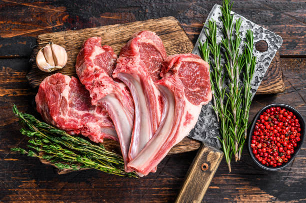 istock Lamb raw chops  steaks on butcher cutting board. Dark wooden background. Top view 1313720143