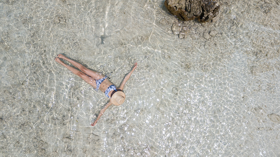 Young woman sunbathing and floating on water very relaxed - Aerial view - Holiday concepts