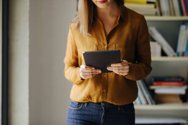 istock Anonymous Businesswoman Standing by the Window in her Office and Using her Tablet 1313726595