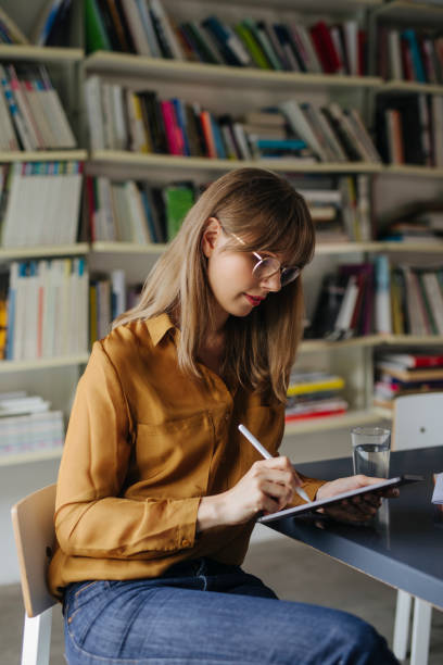 istock Hardworking Student Sitting in the Library and Doing Research for her Master's Thesis 1313726606