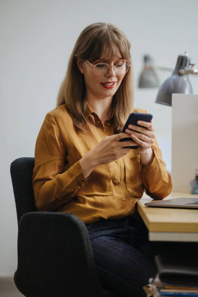 istock Distraction at Work: Blonde Businesswoman Using her Mobile Phone while Sitting at the Office 1313726634