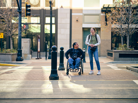 A man in a wheelchair with a young woman in a downtown area.