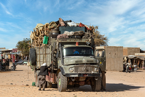 Abeche, Chad - February 14, 2020: Passenger gets into a heavily overloaded old truck. The truck is loaded completely chaotic.