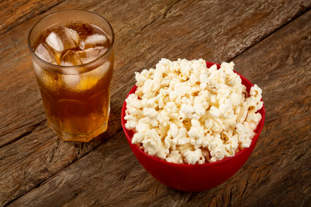 Bowl with salted popcorn and soda on the table. Bowl with salted popcorn and soda on the table. popcorn snack bowl isolated stock pictures, royalty-free photos & images