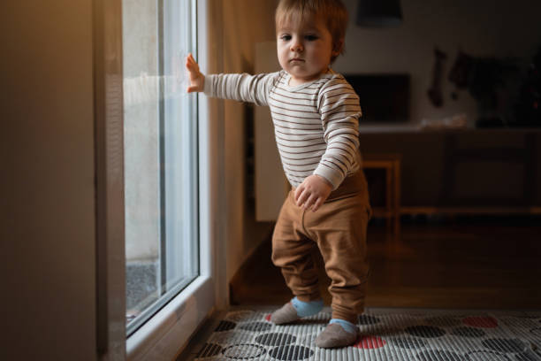 istock Baby boy standing while leaning on the glass door with one hand 1313732325