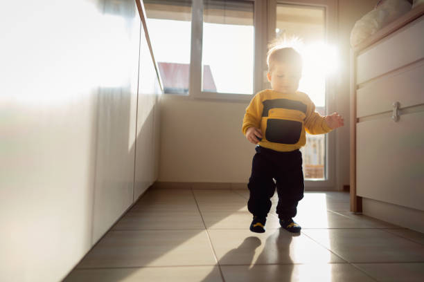 istock Cute baby boy making his steps on the tiled kitchen floor 1313733483